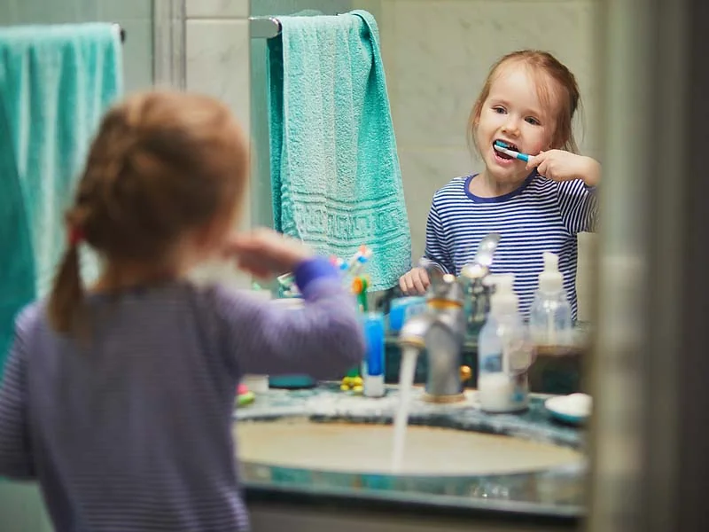 happy girl brushing her teeth in bathroom