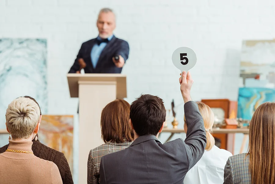 buyer showing auction paddle with number five to auctioneer