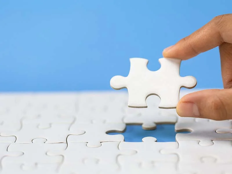 Hand placing the last piece of jigsaw puzzle