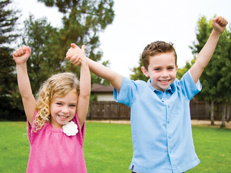 Two young siblings playing outside.