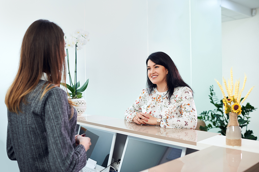 smiling patient speaking with receptionist