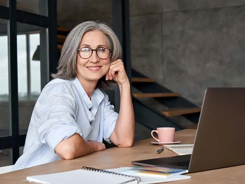 woman sits at desk with laptop